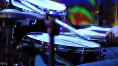 Live concert performance, a drummer energetically playing on stage. The scene captures the dynamic motion of drumsticks hitting cymbals and drums. High quality 4k footage