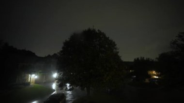 View of suburb street during the storm. Flashing lightening of thunderstorm light up the sky . Close up shot from inside the building. High quality 4k footage