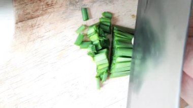 Sarımsak soğanıyla doldurulmuş buğulanmış hamur köftesi yapmak için tahtaya sarımsak soğanı dilimliyorum..