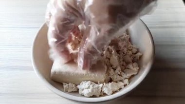 Pişirmeye hazırlanırken tofuyu ezmek için plastik eldiven takan elleri kullanın.. 