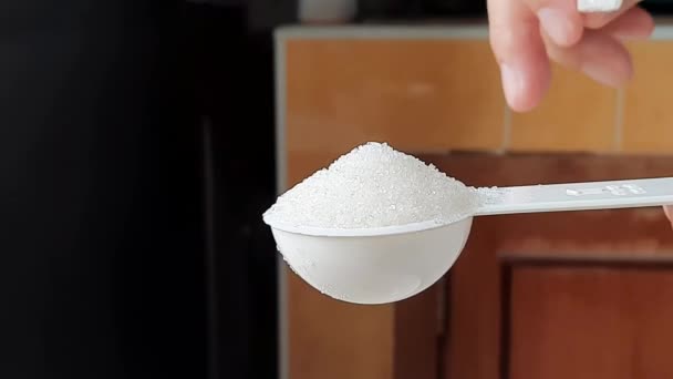 スプーンを測定することから余分な砂糖を削り取るためにプラスチックナイフを使用してください — ストック動画