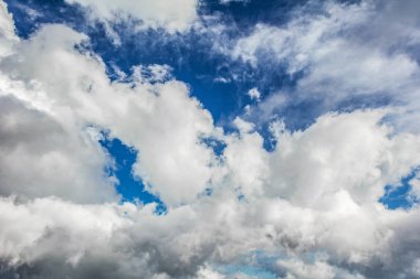 Büyük beyaz bulutlar ve ışık perdeleri ile canlı mavi gökyüzü, parlak doğal hava arkaplan sahnesi.