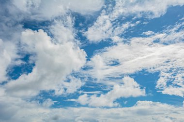 Pofuduk beyaz bulutlarla dolu sakin bir gökyüzü, parlak mavi bir zemin boyunca yayılmış, huzurlu ve rahatlatıcı bir atmosferi yakalıyor.