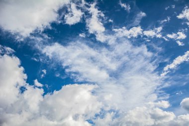 Pofuduk beyaz bulutlarla dolu sakin bir gökyüzü, parlak mavi bir zemin boyunca yayılmış, huzurlu ve rahatlatıcı bir atmosferi yakalıyor.