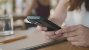 İnternet 'e göz atmak için akıllı telefon kullanan, kafede masada otururken okuyup mesajlaşan serbest çalışan bir kadın. Yaşam tarzı, kahve dükkanında çalışmak. Sosyal medya.