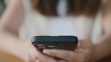 İnternet 'e göz atmak için akıllı telefon kullanan, kafede masada otururken okuyup mesajlaşan serbest çalışan bir kadın. Yaşam tarzı, kahve dükkanında çalışmak. Sosyal medya.