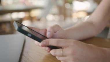 İnternet 'e göz atmak için akıllı telefon kullanan, kafede masada otururken okuyup mesajlaşan serbest çalışan bir kadın. Yaşam tarzı, kahve dükkanında çalışmak. Sosyal medya.