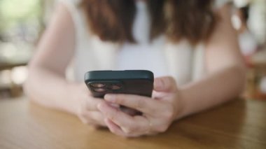 İnternet 'e göz atmak için akıllı telefon kullanan, kafede masada otururken okuyup mesajlaşan serbest çalışan bir kadın. Yaşam tarzı, kahve dükkanında çalışmak. Sosyal medya.