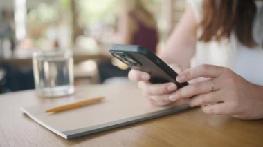 İnternet 'e göz atmak için akıllı telefon kullanan, kafede masada otururken okuyup mesajlaşan serbest çalışan bir kadın. Yaşam tarzı, kahve dükkanında çalışmak. Sosyal medya.