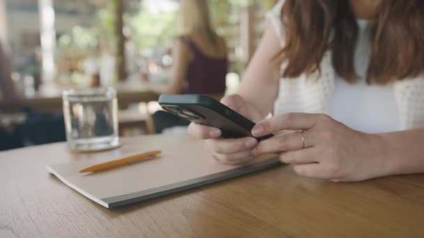 カフェのテーブルに座っている間 インターネットの閲覧 テキストメッセージにスマートフォンを使用しているビジネスフリーランスの女性 ライフスタイル コーヒーショップのコンセプトで働く ソーシャルメディア — ストック動画
