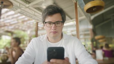 İş adamı, kafede masada otururken interneti taramak, okumak ve mesajlaşmak için akıllı telefonu kullanıyor. Yaşam tarzı, kahve dükkanında çalışmak. Sosyal medya.