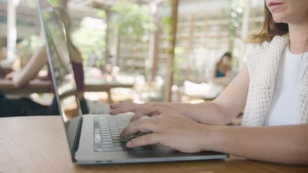 カフェのテーブルに座っている間 インターネットを閲覧するためにラップトップを使用してビジネスフリーの女性 ライフスタイル コーヒーショップのコンセプトでの距離ワーク ソーシャルメディア — ストック動画