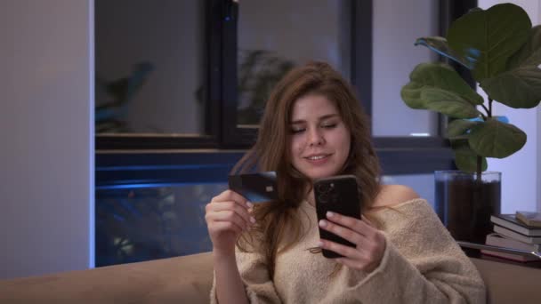 Smilende Ung Kvinde Kunde Holder Kreditkort Smartphone Sidder Sofaen Derhjemme – Stock-video