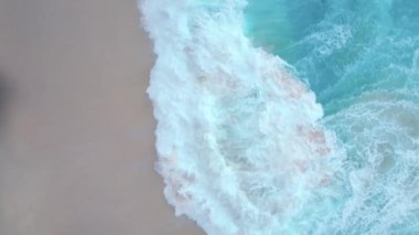 Bali 'de sakin bir tropik plaj manzarası. Kıyıdaki okyanus dalgaları. İnsan yok. İHA havada süzülüyor..