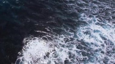 Yukarıdan dalgalar geliyor. Mavi turkuaz okyanusta 4K drone görüntüsü, yavaş çekim. Büyük dalgalar sahil şeridini vurdu. Bali, Endonezya.