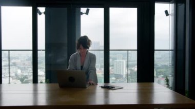 Odaklanmış iş kadını girişimci dizüstü bilgisayarla araştırma yapıyor. Ofis masasında bilgisayar kullanan genç bir kadın. Modern teknoloji taşınabilir bilgisayar üzerinde çalışan meşgul bir işçi.