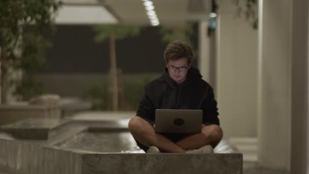 Geschäftsmann Schwarzem Kapuzenpulli Tippt Laptop Sitzt Lotus Pose Pool Der — Stockvideo
