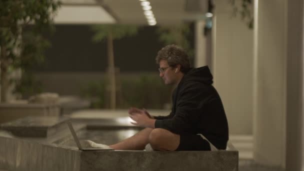 Boční Pohled Muže Sedícího Večer Bazénu Mávající Rukou Mluvícího Videohovoru — Stock video