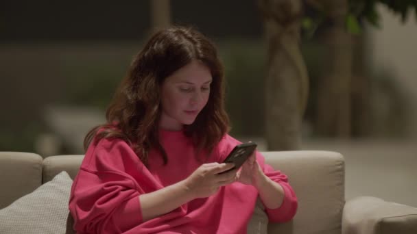 Smiling Beautiful Woman Pink Sweatshirt Texting Phone Sitting Cozy Sofa — Stock Video