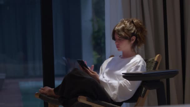 年轻女人坐在扶手椅上 在网上呆了一整天 松懈的女商人在家里感到寒意 在智能手机上打字 网上购物和移动应用的概念 — 图库视频影像