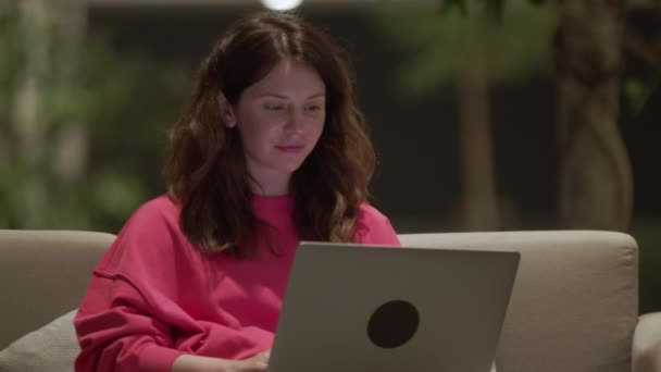 Mooie Jonge Vrouw Roze Sweater Zittend Bank Sms End Laptop — Stockvideo