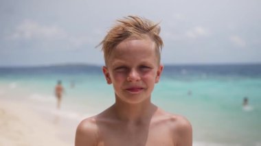 Mutlu beyaz çocuk el sallayarak yaz tatili boyunca sahilde selam veriyor. Video portresi. Yüksek kalite 4k görüntü
