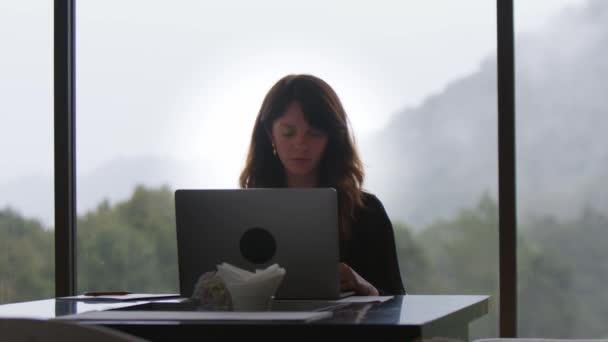 Gülümseyen Esmer Bir Kadın Dizüstü Bilgisayarda Yazıyor Ağaçlara Panoramik Pencere — Stok video