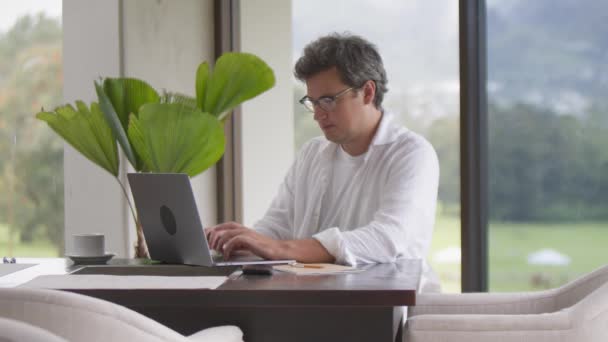 Businessman Eyeglasses Drinking Coffee Typing Laptop Modern Living Room Panoramic — Stock Video