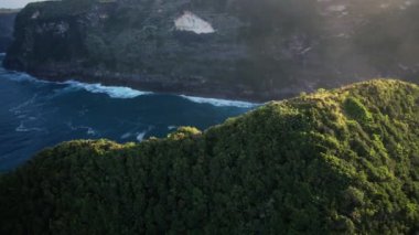 Uçurumla kayalık kumsalın kuş bakışı görüntüsü. Hint Okyanusu kıyısında. Gün batımında doğa ve yolculuk. Güzel doğal yaz tatili seyahat konsepti. Nusa Penida Adası.