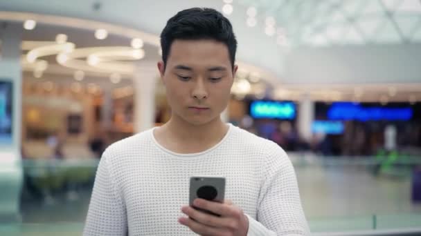 Отслеживающий Портрет Красивого Азиатского Мужчины Белой Толстовке Идущего Прокручивающего Смартфон — стоковое видео