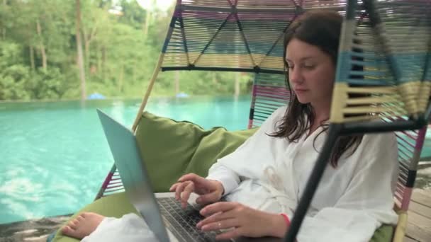 Приваблива Жінка Білому Халаті Використовуючи Ноутбук Смартфон Нескінченній Терасі Басейну — стокове відео