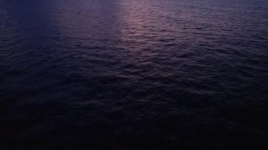 Okyanus suyunun üzerinde tropik altın gün batımı. Güneş deniz manzarasına yansıyor. İnsansız hava aracı atışı yok. Güneşli şafakta sakin bir su manzarası. Yaz tatili. Bali 'de tropik tatil.