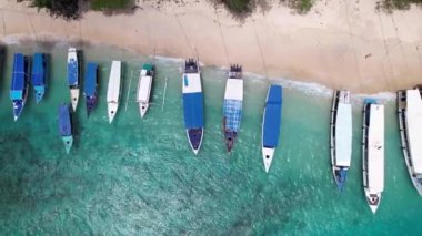 Gili Trawangan sahilindeki sürat teknesi limanının yakınındaki teknelerin havadan görüntüsü. İHA kıyı şeridi boyunca uçuyor.