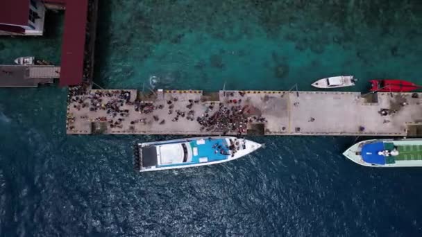 明確な青い海水とピア上の観光客がフェリー スピードボート ロンボクインドネシアを待っている朝の風景のギリ トラワンガン港の空中ビュー ドローンが桟橋のそばで飛んでいる — ストック動画