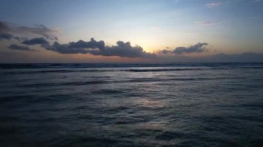 Gün batımında okyanus yüzeyinde uçan insansız hava aracının görüntüsünü kaldırıyorum. Gili Trawangan Adası, Lombok. Yüksek kalite 4k görüntü