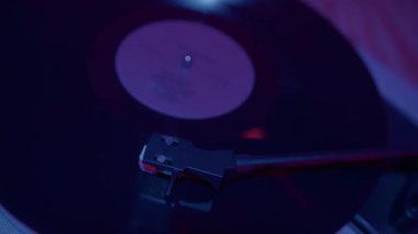 Bu resimde, bir plak çalara sanatsal bir yaklaşım sergileniyor, modern ortamlarda müzik ve yaratıcılığın havasını yükselten ortam ışıklarıyla aydınlatılıyor..