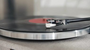 Bu resim, pikabın karışık detaylarını vurgulayan, plağı çalarken, retro bir titreşim yakalayan, stili olan bir vinil pikabın yakın çekimini içerir..
