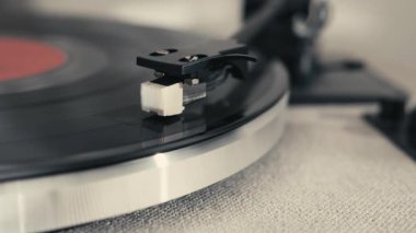 Bu resim, pikabın karışık detaylarını vurgulayan, plağı çalarken, retro bir titreşim yakalayan, stili olan bir vinil pikabın yakın çekimini içerir..