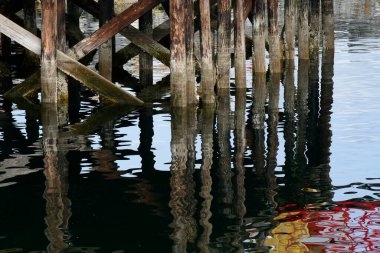 Okyanus suyuna yansıyan eski ahşap iskele sütunlarının görüntüsü..