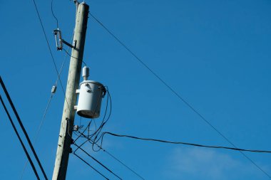 Parlak mavi gökyüzüne karşı güç transformatörünün ve elektrik hatlarının görüntüsü.. 