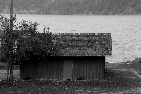 湖の端に捨てられた古い家の黒と白のイメージ — ストック写真