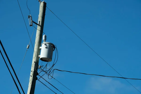 stock image An image of a power transformer and power lines against a bright blue sky. 
