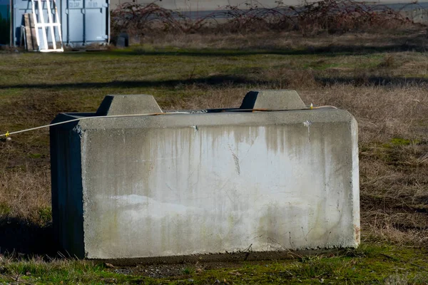 n image of a single concrete barrier left behind in an open field.
