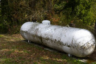 Ev ısıtmasında kullanılan çok büyük ve paslı bir propan depolama tankının görüntüsü..