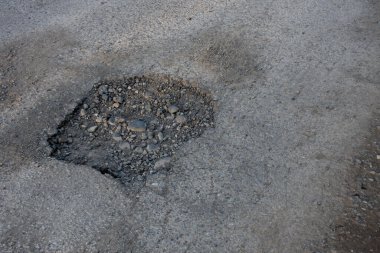 Çok gezilmiş bir yolun ortasındaki çok derin bir çömlek deliğinin görüntüsü..