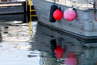 İki kırmızı şamandıralı küçük metal bir balıkçı teknesinin su yansıması..