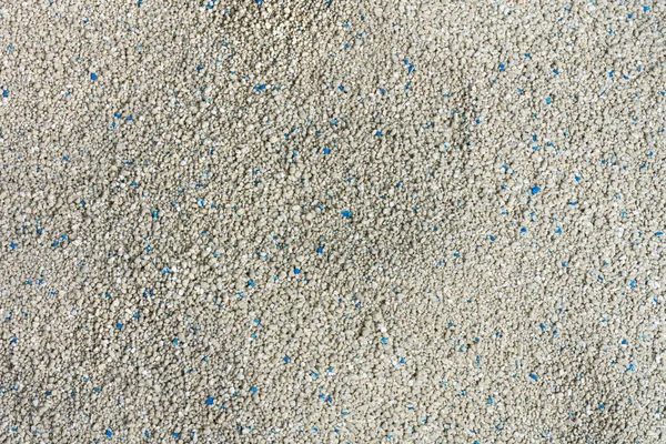 An abstract image of the texture of fresh cat litter with blue flecks.