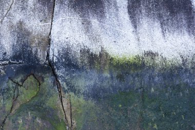 Kısmen yosunla kaplanmış büyük çatlak bir kayanın üzerindeki dokunun soyut bir görüntüsü.. 