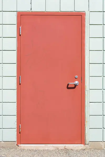 赤い塗料を薄くした古い金属製の外装ドアのイメージ ストックフォト