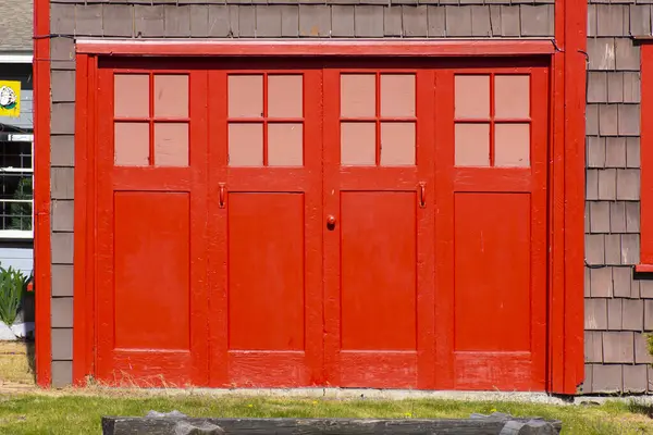 明るい赤いペンキが付いている古いヴィンテージ様式のガレージのドアのイメージ ロイヤリティフリーのストック画像